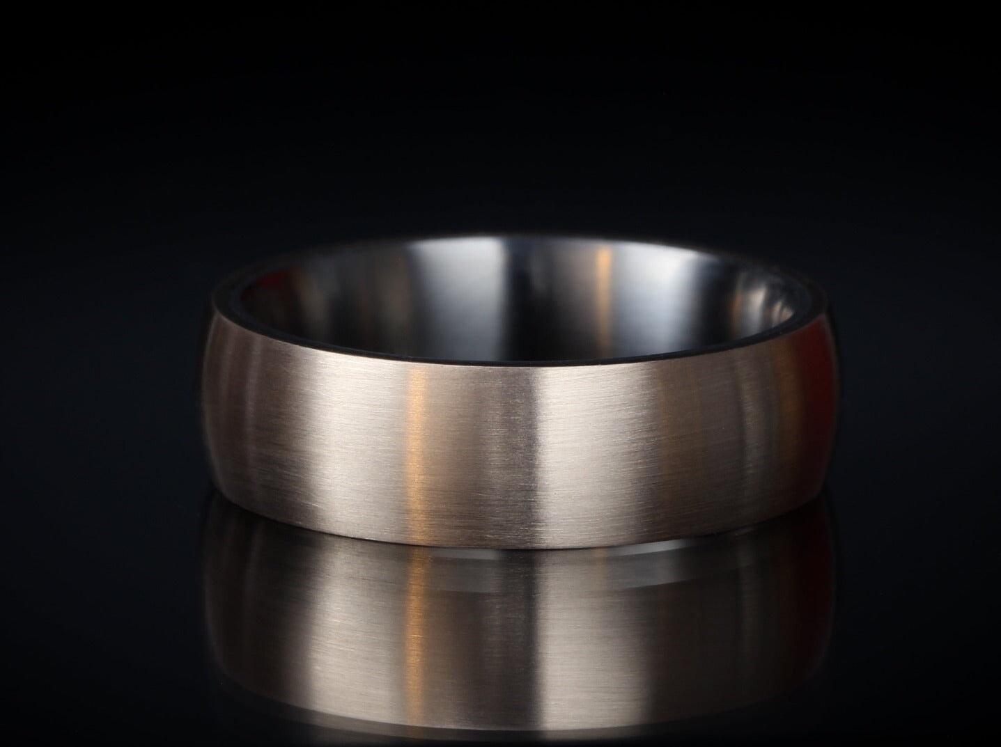 Brushed "Wilde" titanium ring on a reflective surface